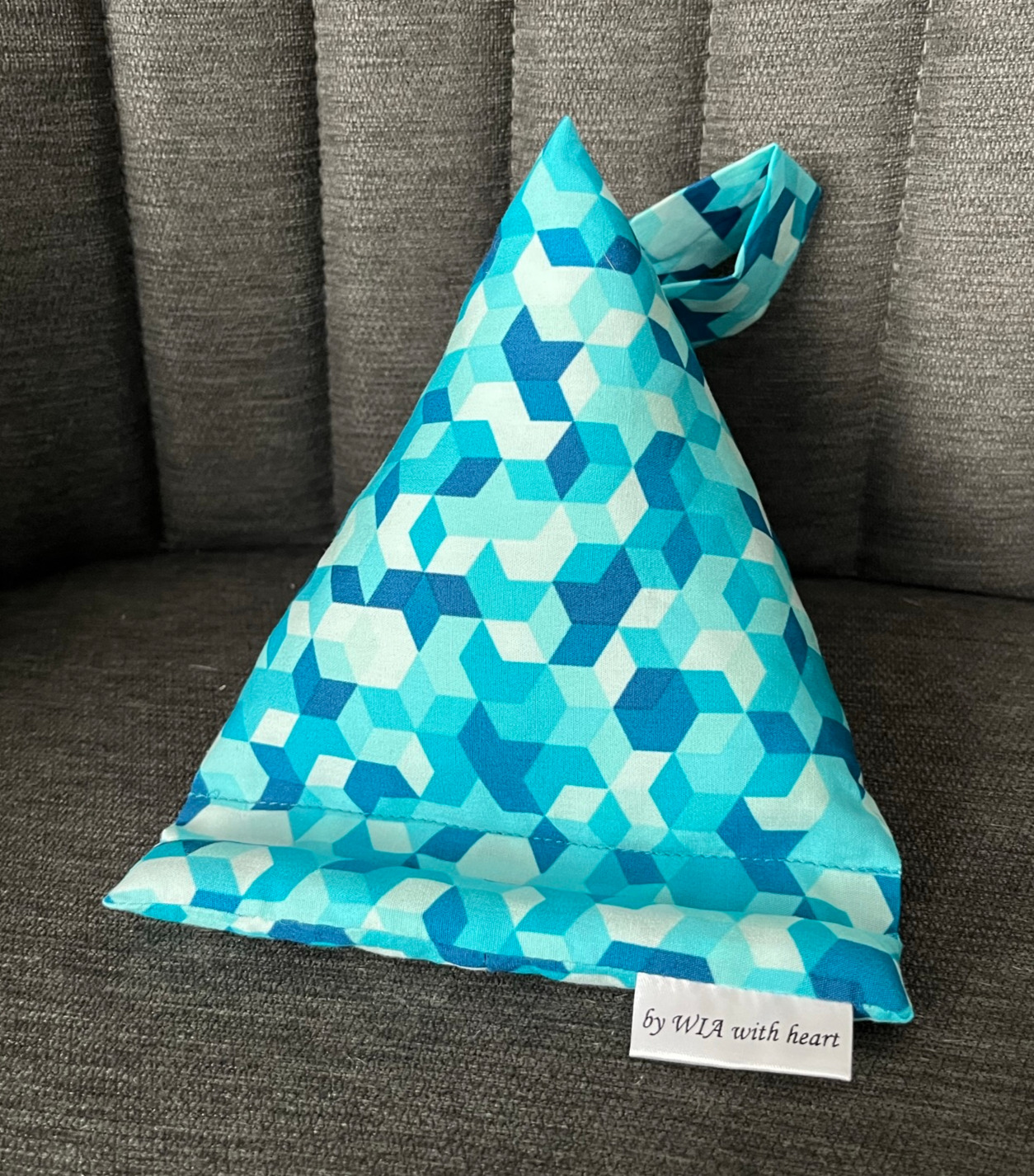 Dreieckiger Handysitzsack in Türkis mit geometrischem Würfelmuster auf grauem Sofa