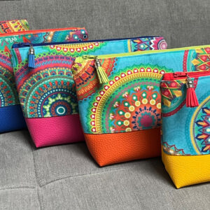 Fünf Kosmetiktaschen mit Mandalamuster und farbigem Kunstlederboden auf grauem Sofa