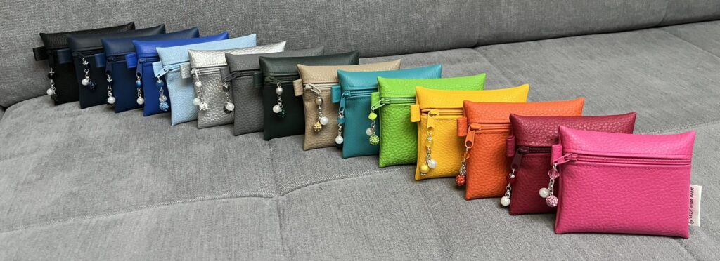 Kunstledertäschchen in dunklen und kräftigen Farbtönen auf hellem Sofa
