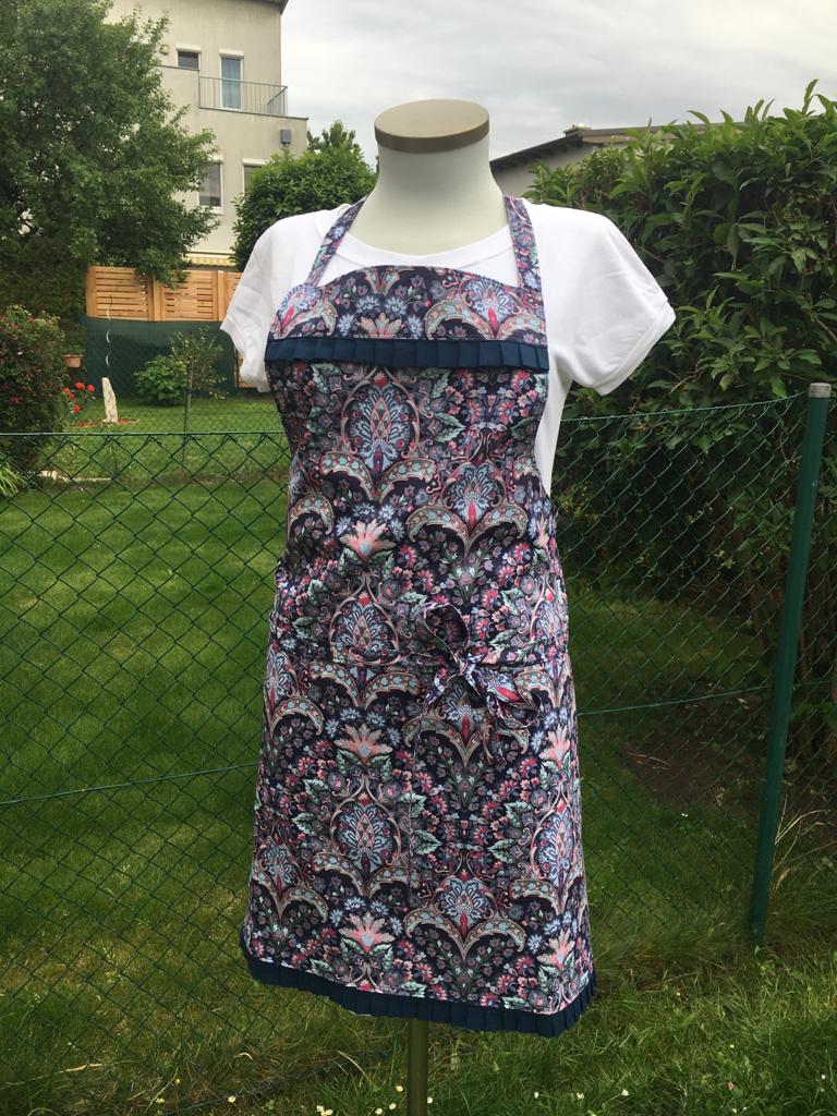 Schneiderpuppe mit geblümter Schürze über weißem T-Shirt im Garten