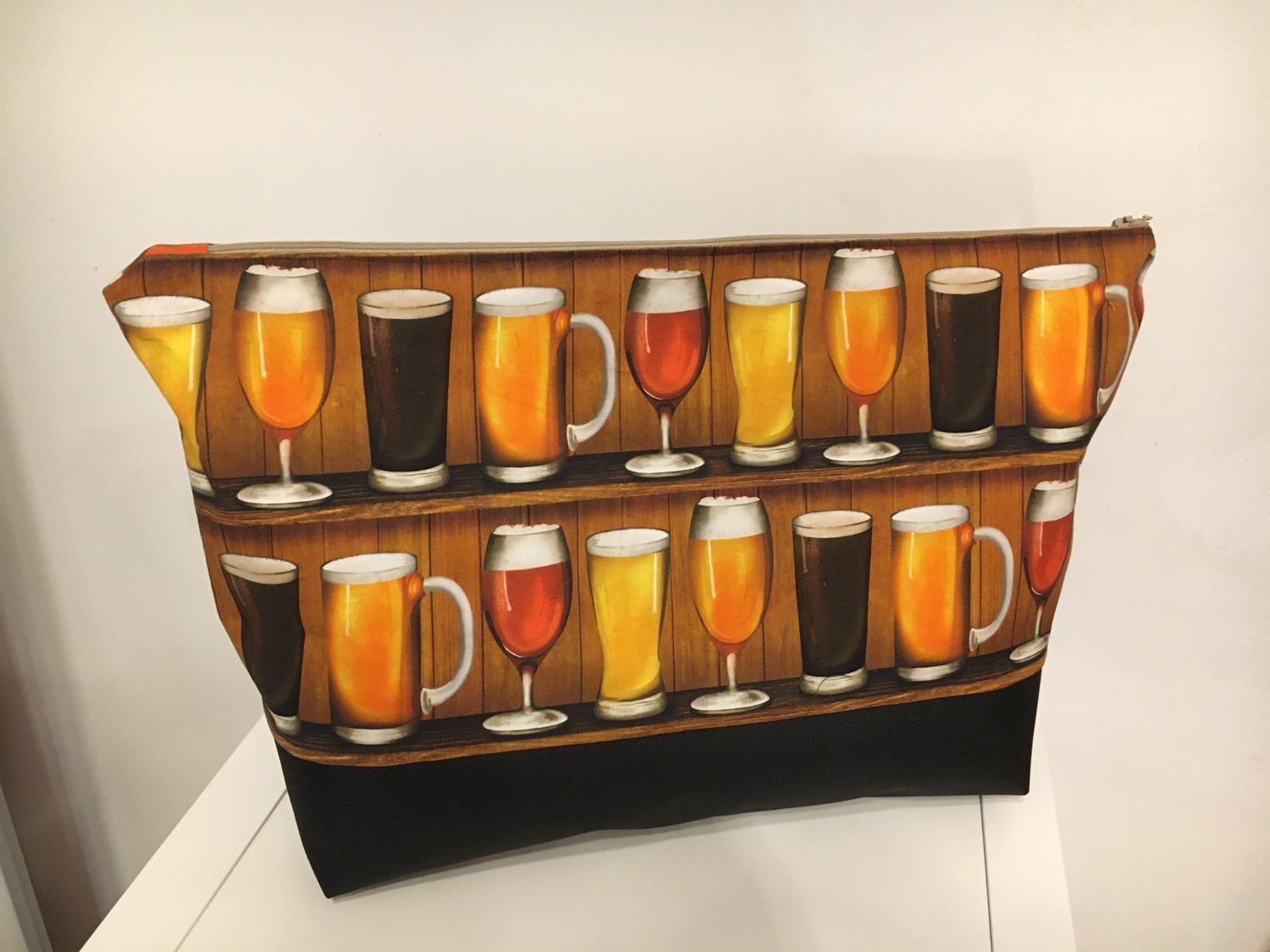 Stofftasche mit Print von Biergläsern auf Holzregalen und schwarzem Boden